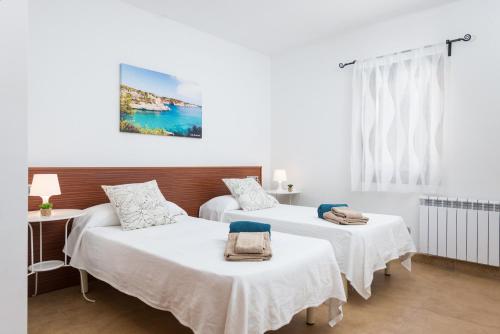 two beds in a room with white walls at Can Fiol in Portocolom