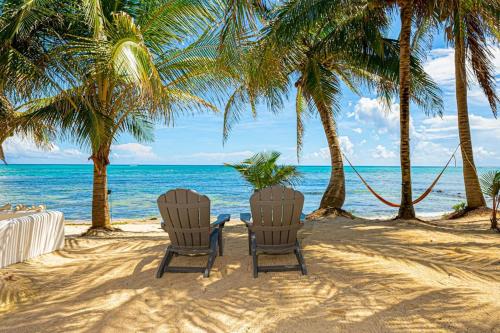 two chairs on a beach with palm trees and the ocean at Oceanfront home with beach access pool balconies & waterfront hammocks - Villa Sol in Tulum