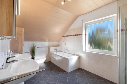 a bathroom with two sinks and a tub and a window at Haus Langer in Oberkirch