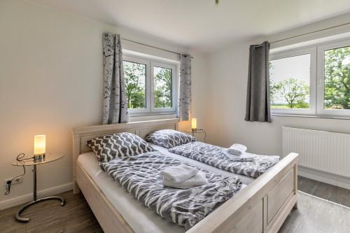 two beds in a bedroom with two windows at Föhr in Galmsbüll