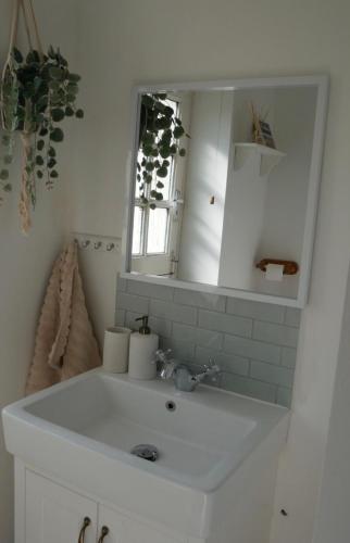 a bathroom with a white sink and a mirror at Dickens HideAway in Hollington