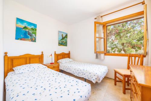two beds in a room with a desk and a window at Traumblickwohnung Montemar 19 in Sóller