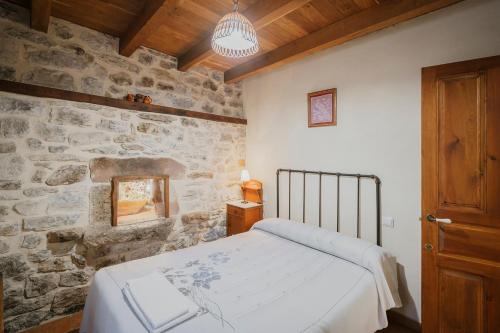 a bedroom with a bed and a stone wall at Casa Lope in Dobres