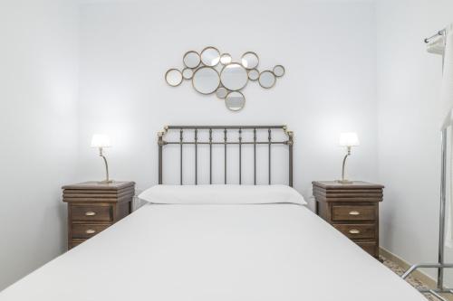 a white bedroom with a large bed and two night stands at Casa Pepa in Barbate