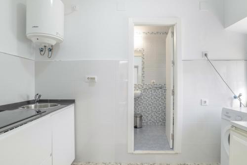 a white kitchen with a sink and a shower at Casa Pepa in Barbate
