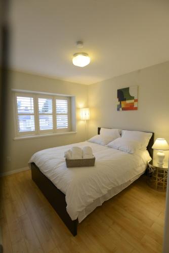 a bedroom with a large bed with white sheets and pillows at Marpole Guest House in Vancouver