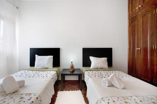 two twin beds in a room with a table at A O - Apartamento Aires in Peniche
