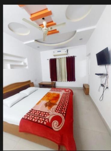 a bedroom with a bed with a red blanket and a ceiling at Hotel prayag with ev car station 7,4kw in Nāthdwāra