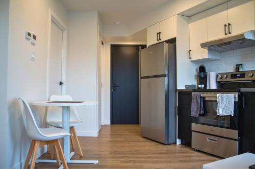 a small kitchen with a table and a refrigerator at Appart'hôtel Vivéo - Par Aneyro in Quebec City
