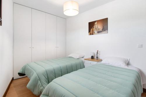 two beds in a room with white walls at Apartamento Bali com Piscina in Apúlia