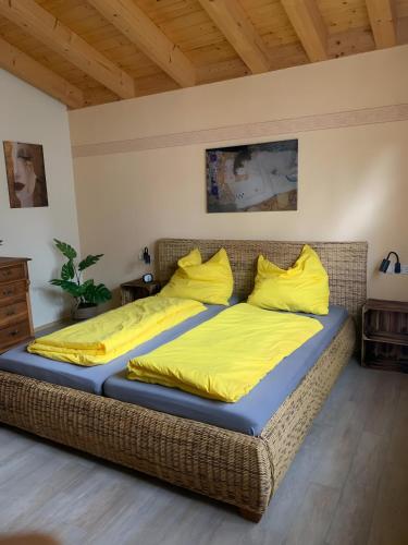 a bed with yellow sheets and pillows in a room at Haus Pluto in Deggenhausertal