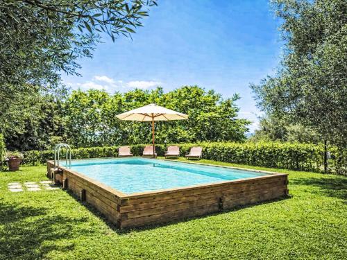 a swimming pool with an umbrella and chairs at Apartment Ginestra by Interhome in Perugia