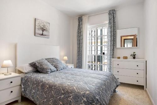 a white bedroom with a bed and a window at Apartamento Atlántico in Barbate
