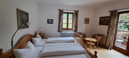 a bedroom with two beds and a table and a window at Haus am Kurgarten - Seeberg in Bayrischzell