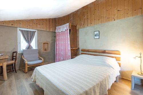 a bedroom with a bed and a chair and a window at Petit Havre Cosy Vue Pyrénénées in Estibeaux