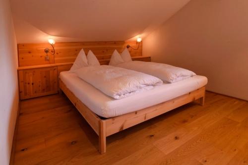 a large bed in a room with wooden floors at Rosengartnerhof Apt Maultasch in Terlano