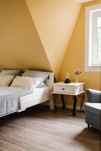 a bedroom with yellow walls and a bed and a table at Landhaus Elbenberg in Naumburg