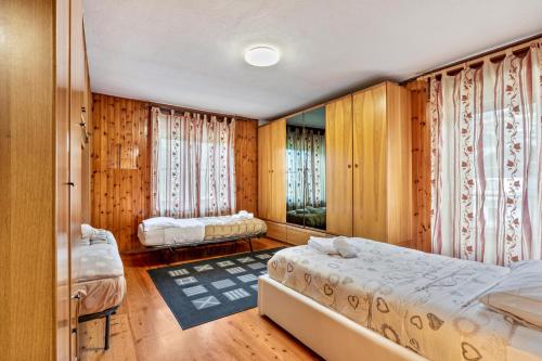 two beds in a room with wooden walls and windows at Alloggio Chez Favre in Blavy