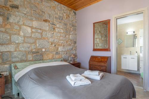 a bedroom with a stone wall with a bed and towels at Angelina’s Stone Village House in Valíra