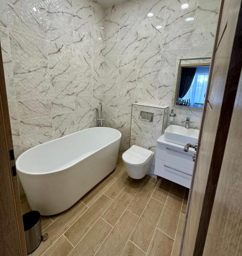 a bathroom with a tub and a toilet and a sink at Raudondvaris holiday home in Raudondvaris