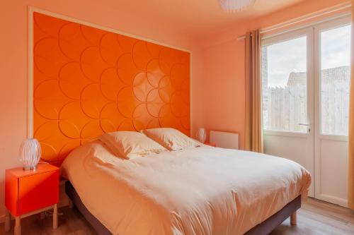 a bedroom with a bed and a orange wall at La Pause Picarde - Baie De Somme 1 in Franleu