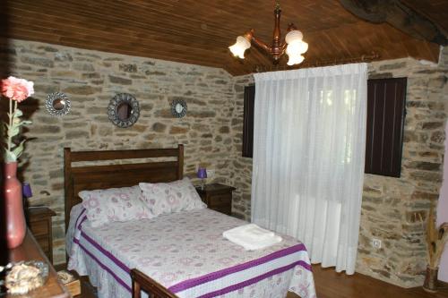 a bedroom with a bed and a stone wall at O Bolaño Apt 2 in Villarino de Conso