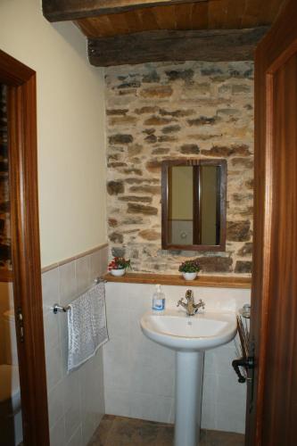 a bathroom with a sink and a stone wall at O Bolaño Apt 2 in Villarino de Conso