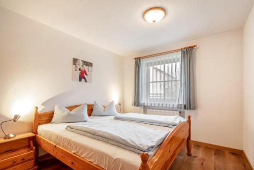 a bedroom with a bed with white sheets and a window at Fewo Brünnstein - Nr 11 Pool, Sauna in Oberaudorf