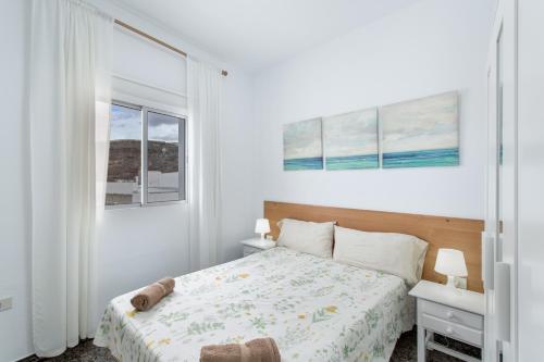 a white bedroom with a bed and two windows at Atico martin in San Nicolás