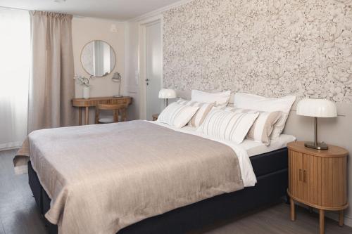 a white bedroom with a large bed and a mirror at Osterøy Minihotell in Lonevåg
