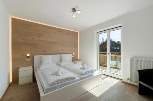 a bedroom with a white bed with a wooden wall at Premium App Hofer Elisabeth in Villabassa
