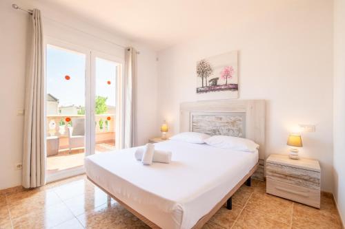 a white bedroom with a large bed and a window at Villa Gaviota in Muro