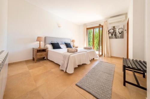 a white bedroom with a bed and a window at Sa Lluna in Sant Josep