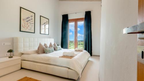 a white bedroom with a bed and a window at Moli De Can Cristan in Muro
