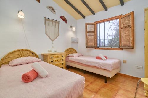 a bedroom with two beds and a desk and window at Casa Oliana in Cómpeta