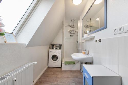 a bathroom with a sink and a washing machine at Ferienwohnung Janina in Norddeich