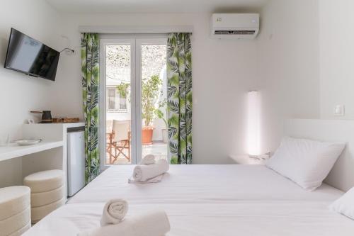 a white bedroom with a large bed with towels on it at A Tinian Room 3 in Tinos