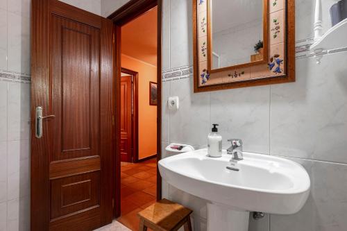 ein Badezimmer mit einem weißen Waschbecken und einem Spiegel in der Unterkunft Lorences B in Caunedo