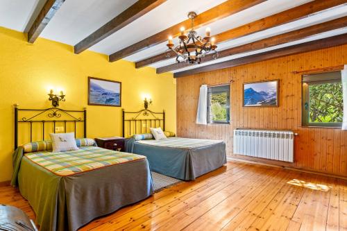 Zwei Betten in einem Zimmer mit gelben Wänden und Holzböden in der Unterkunft Lorences B in Caunedo