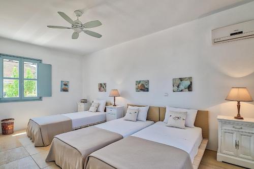 a bedroom with three beds and a ceiling fan at Villa Afroditi A in Antiparos