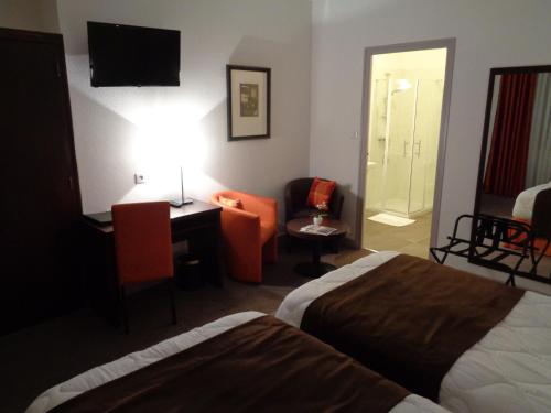 a hotel room with two beds and a desk and a chair at Hotel de Montaulbain in Verdun