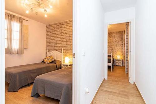 a bedroom with two beds and a brick wall at Casa Jimena in Vejer de la Frontera