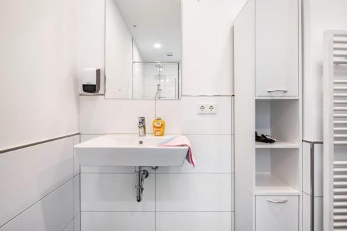 a white bathroom with a sink and a mirror at Die Alter Schwede Wohnung 1 in Vechta