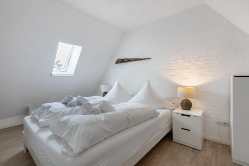 a white bedroom with a large bed with white sheets at Häuschen Seerobbe in Böhl