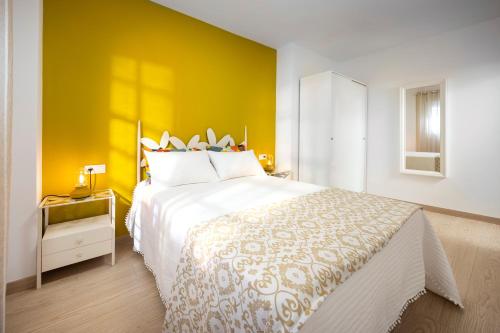 a bedroom with a large bed with a yellow wall at Capricho Torre del mar in Torre del Mar