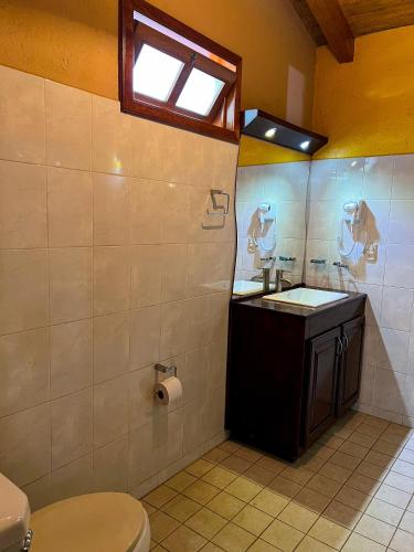 a bathroom with a toilet and a sink and a window at Cabañas Rosy in Mazamitla
