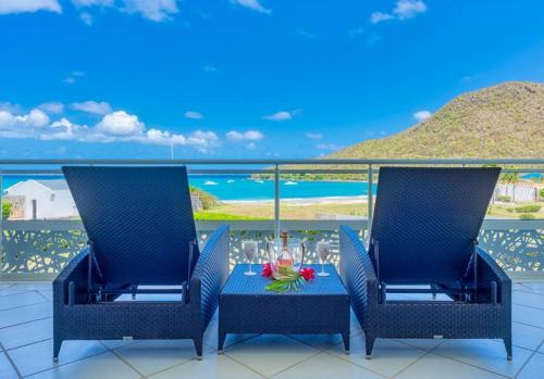 a table and chairs on a balcony with a view of the ocean at Le Domaine Anse Marcel Beach Resort in Anse Marcel 