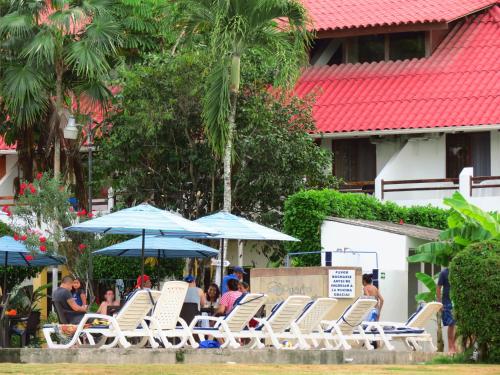 a group of lounge chairs and umbrellas at a resort at Hotel Puerto Ballesta in Tonsupa