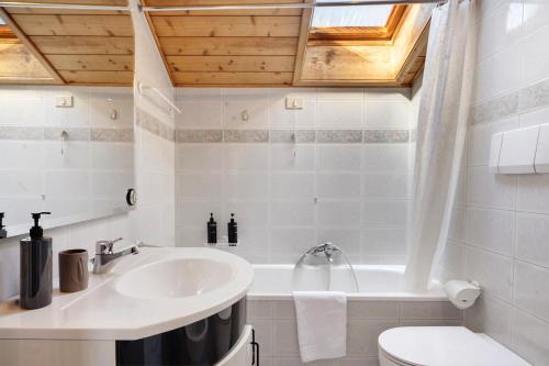 a bathroom with a sink and a tub and a toilet at Apartment Holzsuite in Fondo