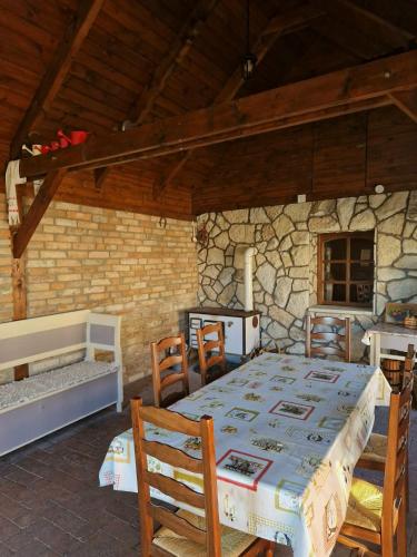a room with a table and chairs and a stone wall at Szilvaliget Vendégház in Tolcsva